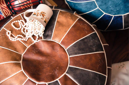 Camel faux leather pouf top view with decorative beads and mug on surface