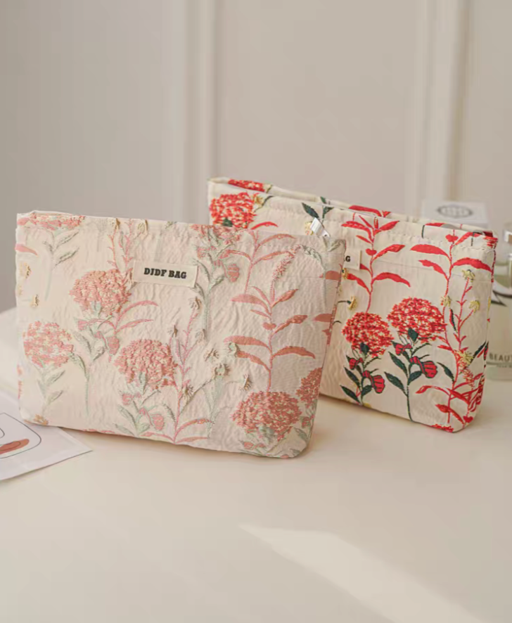 Botanical Embroidered Zip Makeup Pouch showing pink and red floral embroidered designs displayed together on table