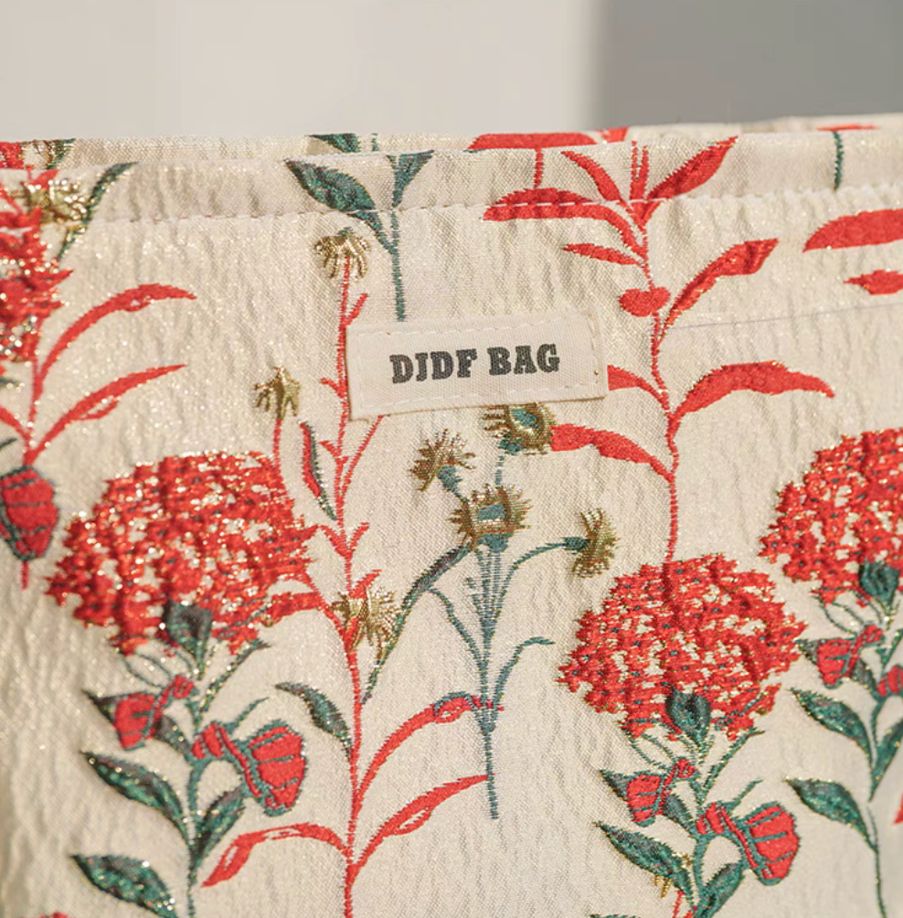 Close-up of Botanical Embroidered Zip Makeup Pouch in red floral embroidery showing textured fabric and brand label
