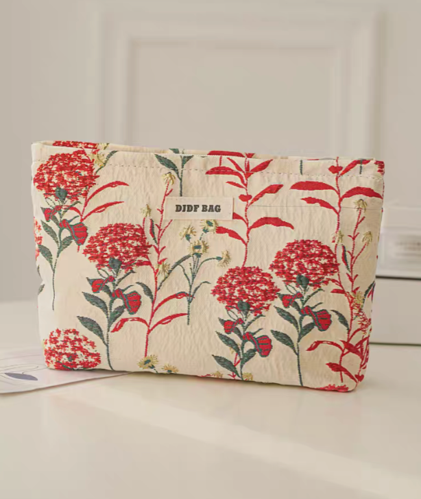 Botanical Embroidered Zip Makeup Pouch in red floral embroidery standing upright on table with lipstick beside