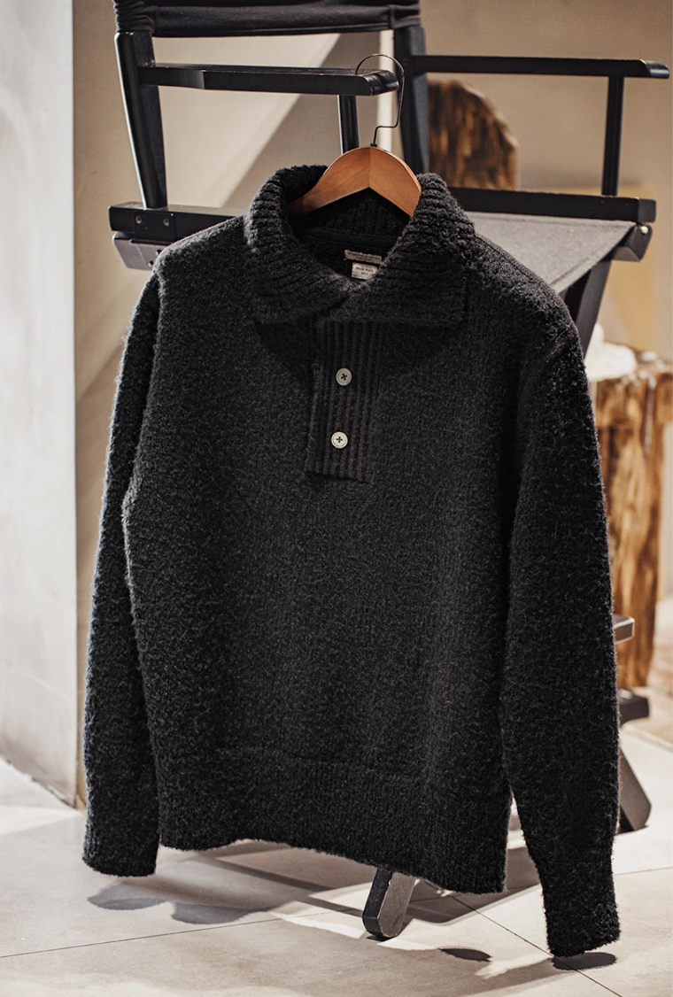 Black Bouclé Knit Polo Sweater hanging on wooden hanger
