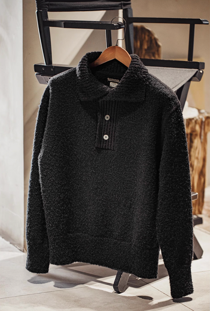 Black Bouclé Knit Polo Sweater hanging on wooden hanger
