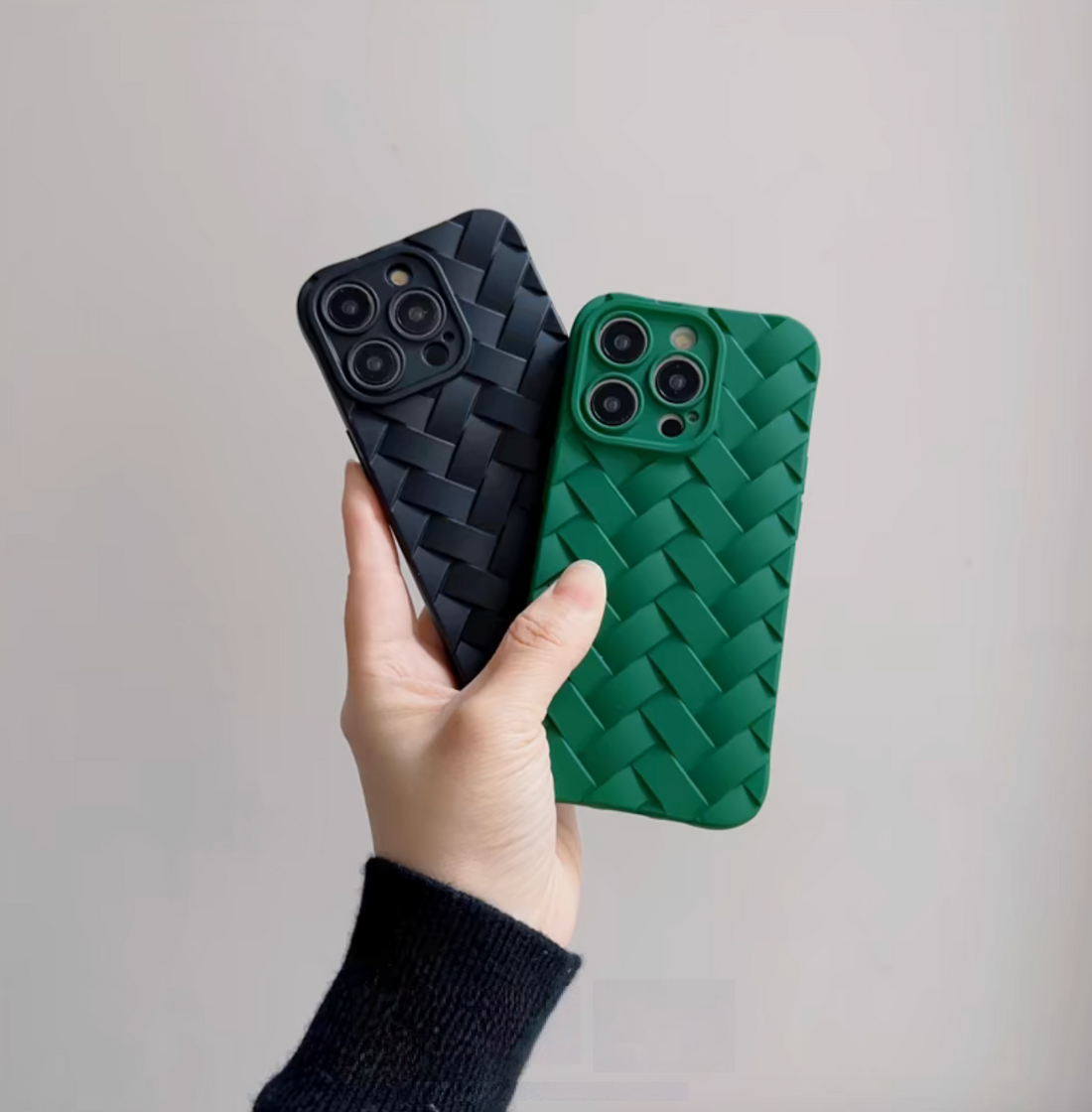 Black and green braided silicone phone cases held in hand showing woven texture and raised camera protection