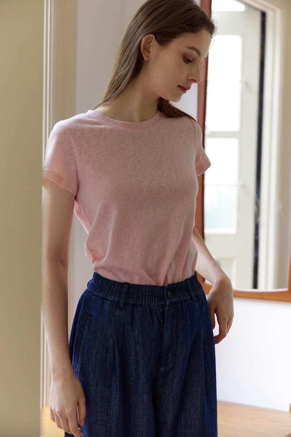 Model wearing Breeze Sheer Classic Tee in pink styled with dark skirt highlighting soft sheer fabric and relaxed silhouette