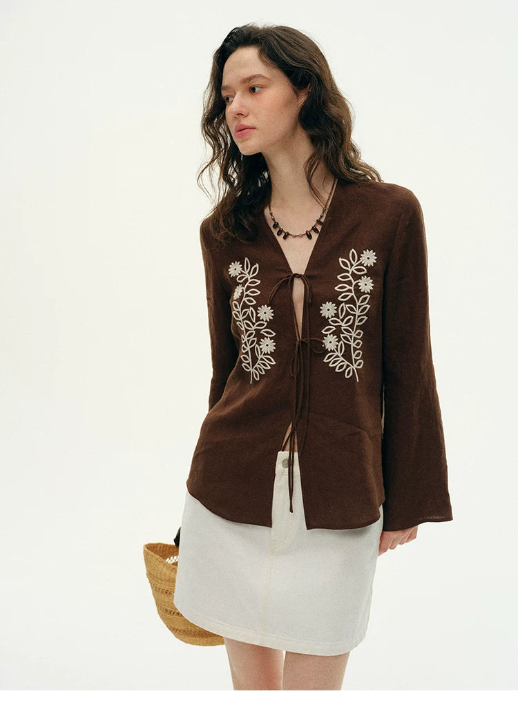Woman wearing brown embroidered hemp cardigan with white mini skirt, side view