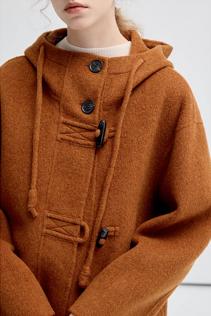 Close-up of the brown hooded coat front, showing buttons, toggles, and drawstring design.