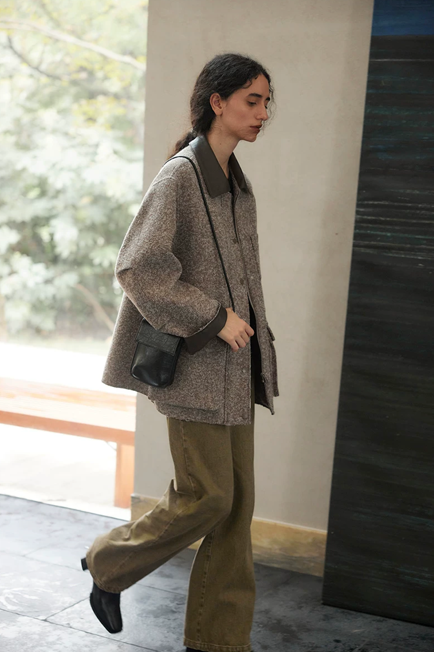 Brown boxy wool tweed jacket in motion, showing the dropped shoulders and leather-look cuff