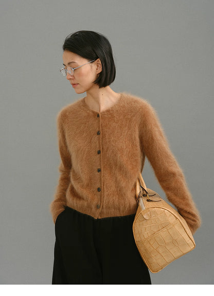 Side profile of caramel brushed cashmere cardigan styled with a beige bag.