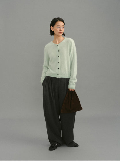 Woman wearing mint green brushed cashmere cardigan with gray wide-leg trousers.