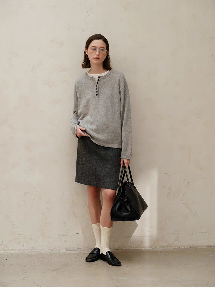 Full body view of model wearing light gray Buttoned Henley Knit Pullover Sweater paired with skirt and loafers