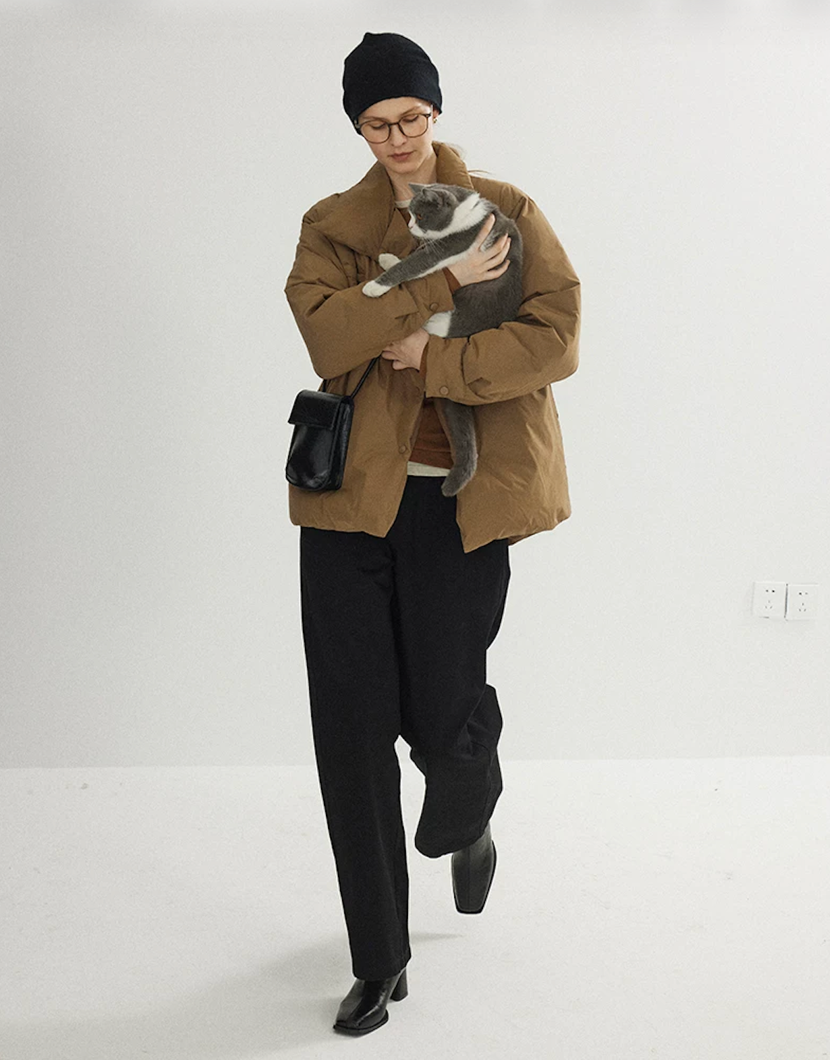 Camel relaxed down jacket in motion, showing the straight H-line cut and snap front