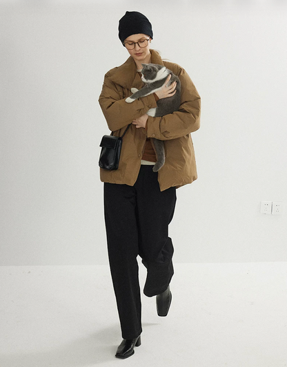 Camel relaxed down jacket in motion, showing the straight H-line cut and snap front