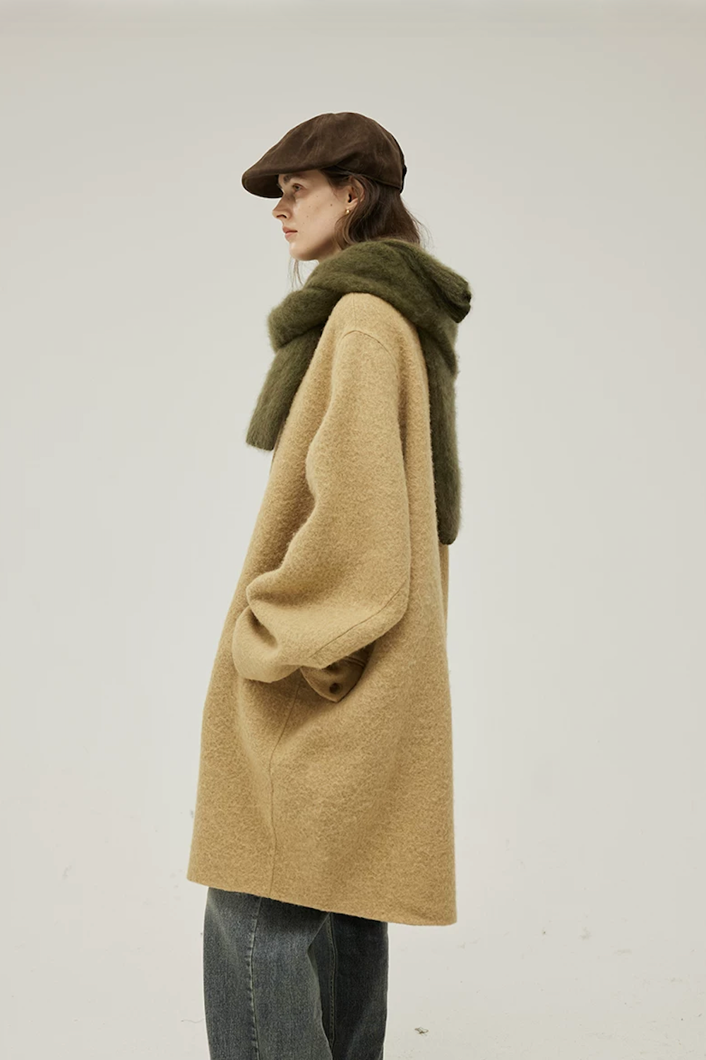 Side profile of a Camel cocoon wool coat showing the rounded body and buttoned flap pocket