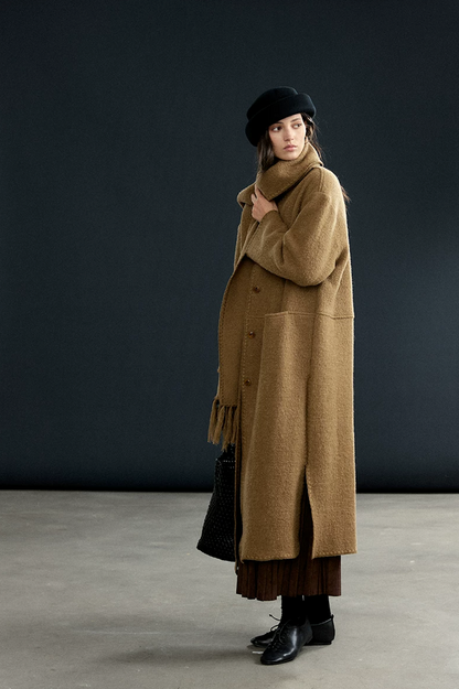 Camel long wool coat with matching fringed scarf wrapped high, showing blanket-stitch edging and side slit