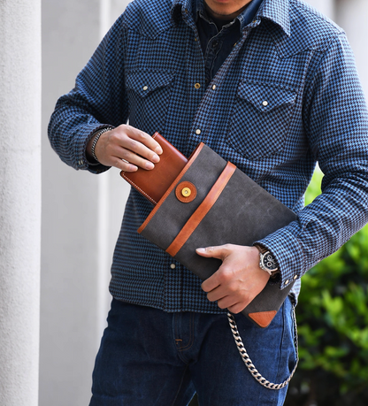 Close-up of charcoal gray canvas laptop sleeve being opened to place a brown leather wallet inside.