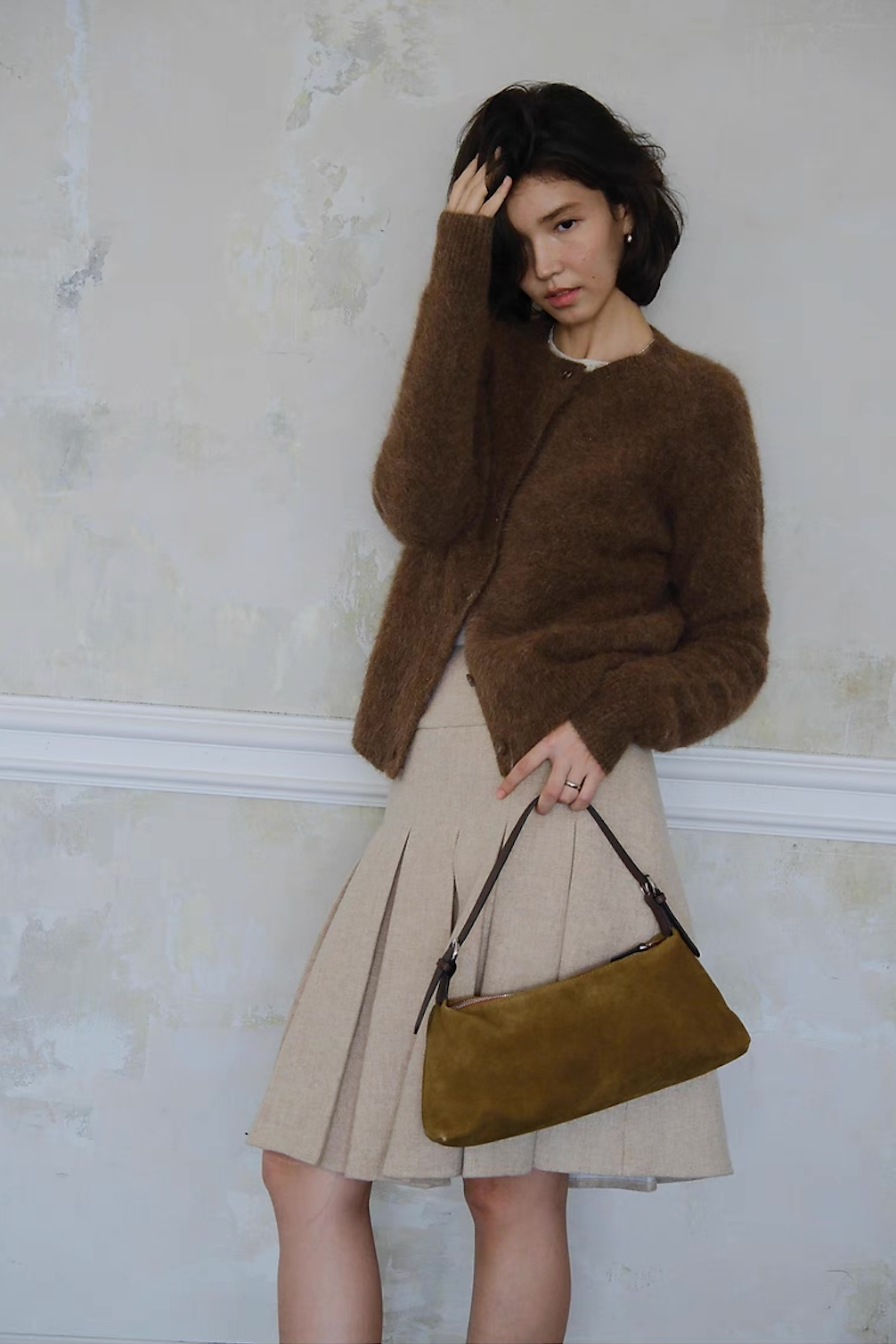 Women’s brown cardigan styled with beige skirt and suede bag