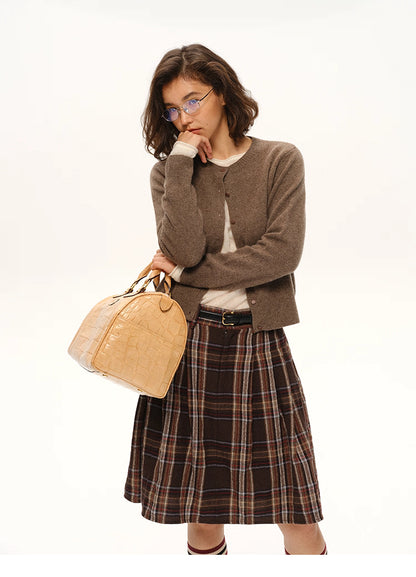 Woman wearing coffee brown yak-cashmere cardigan paired with plaid skirt