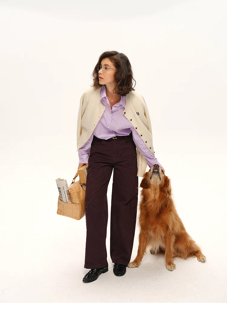 Full-body shot of model wearing cream cardigan and striped shirt while petting golden retriever