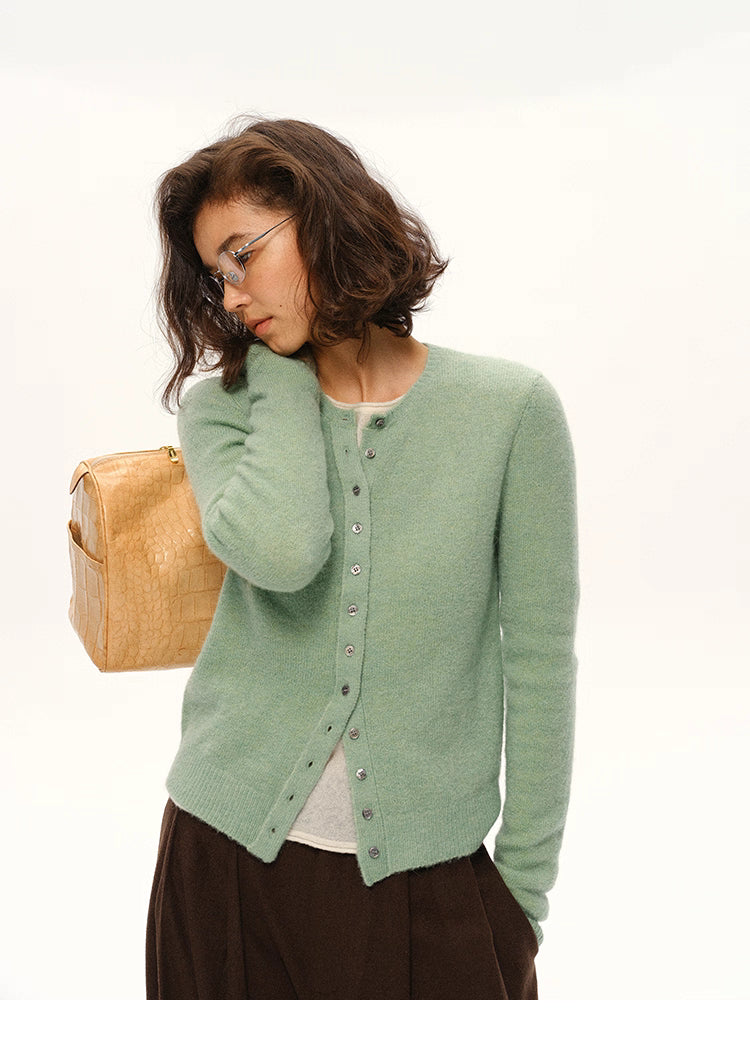 Woman wearing mint green alpaca cardigan with beige shoulder bag, front view