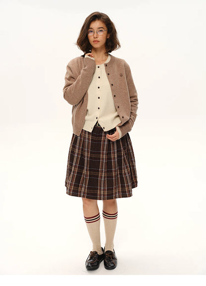 Model in mocha brown wool logo cardigan paired with cream knit and brown plaid skirt, full-body standing pose