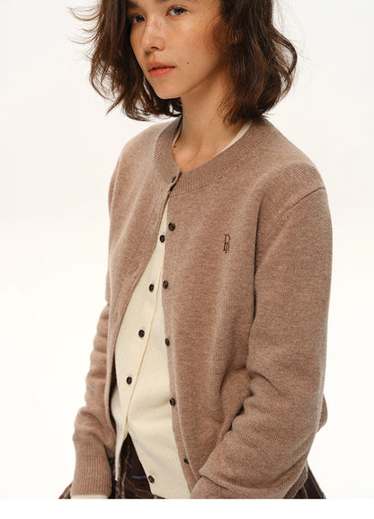 Mid-shot of model wearing mocha wool cardigan layered over cream knit top, soft natural expression