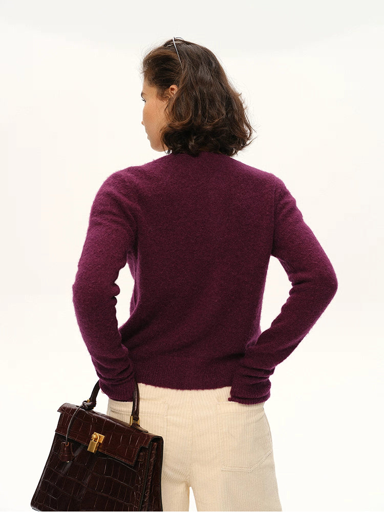 Back view of woman wearing plum purple alpaca cardigan holding dark croc handbag