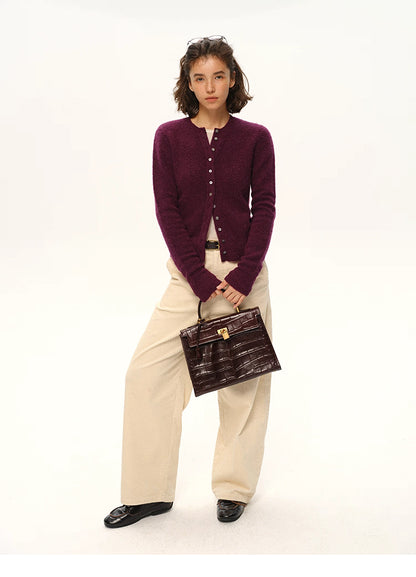 Woman wearing plum purple alpaca cardigan with cream pants and dark croc handbag