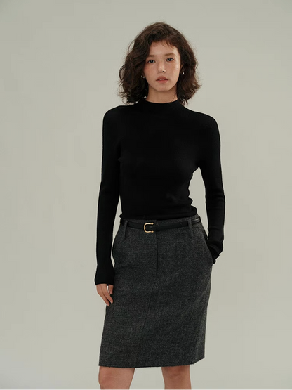 Woman in black cashmere sweater with grey pencil skirt – minimalist winter knitwear style.