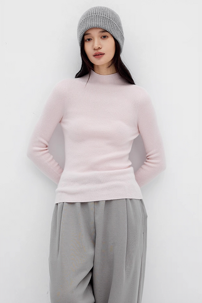 Woman in soft pink slim-fit cashmere sweater with grey wide-leg pants and grey beanie – cozy winter outfit.