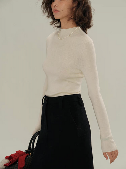 Side view of woman wearing ivory white slim-fit cashmere sweater with black skirt – elegant silhouette.