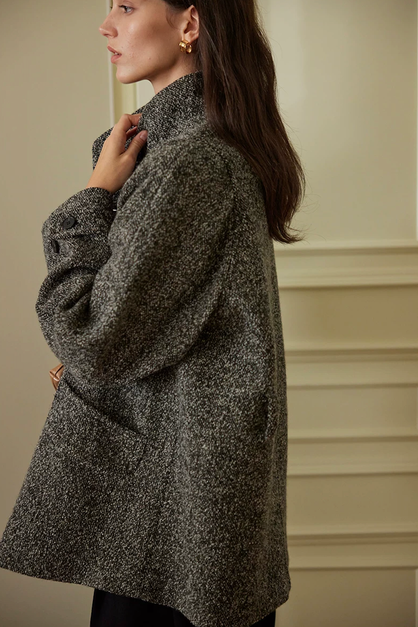 Side profile of a Charcoal wool tweed jacket showing the stand collar, patch pocket, and cuff tab
