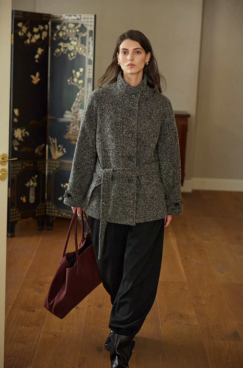 Charcoal wool tweed jacket buttoned and belted at the waist, in motion