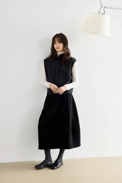 Full-length view of woman in Charcoal Gray cable knit wool vest over an ivory turtleneck with a black midi skirt