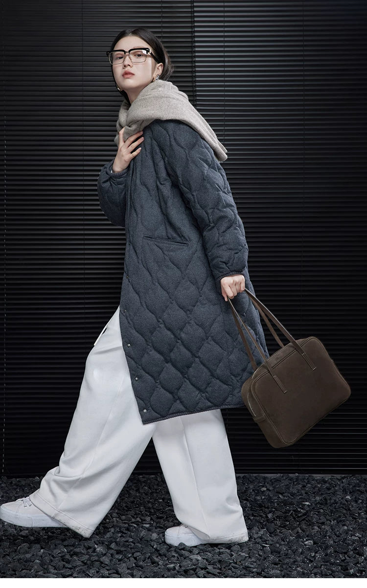 Side view of a Charcoal longline quilted coat in motion, showing the ribbed cuff and hem