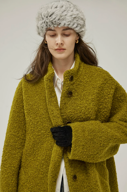 Close-up of a Chartreuse bouclé wool coat with stand collar, tonal brown buttons, and wide sleeve