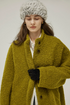 Close-up of a Chartreuse bouclé wool coat with stand collar, tonal brown buttons, and wide sleeve