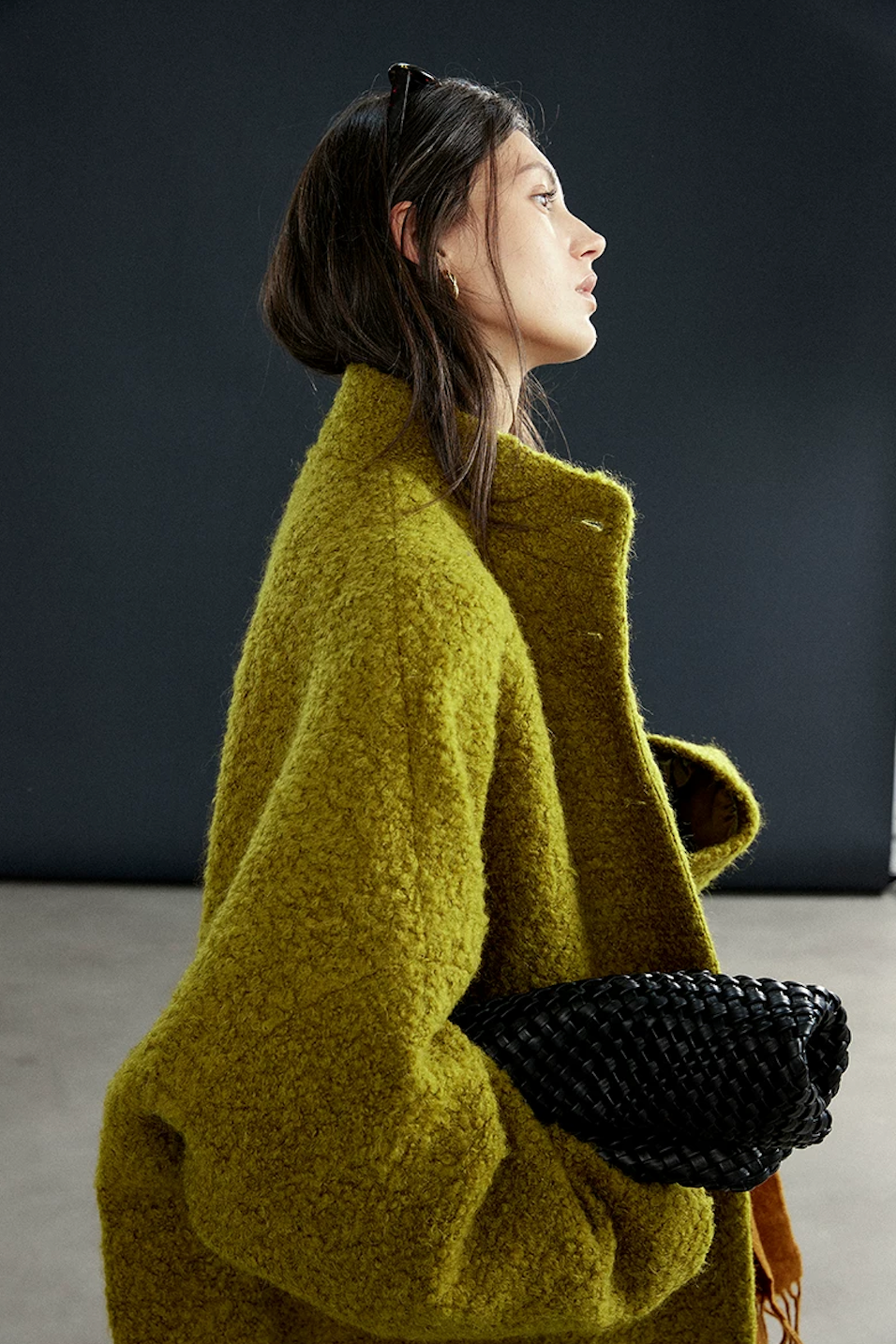 Side profile of a Chartreuse bouclé wool coat showing the cocoon shape and deep sleeve volume