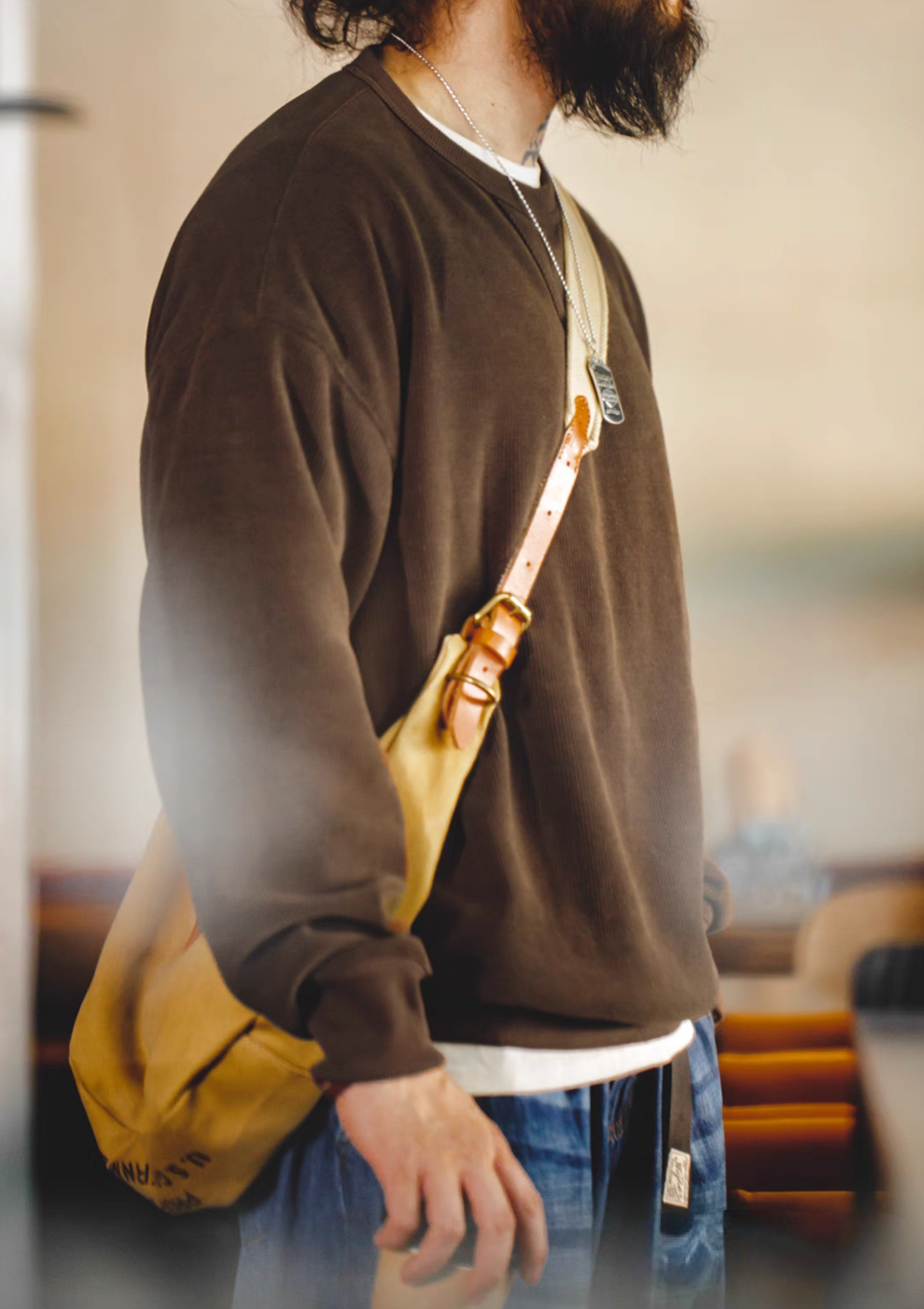 Coffee chenille crew sweater side profile showing relaxed silhouette and everyday styling with shoulder bag
