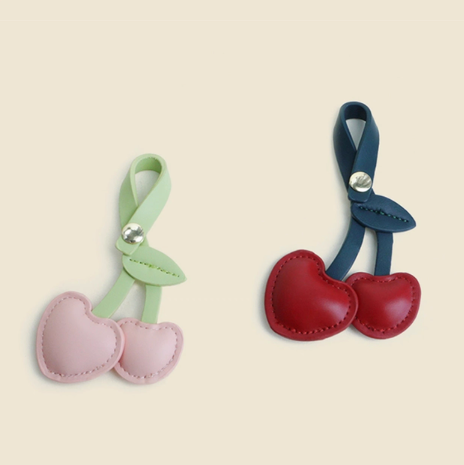 Cherry heart PU leather keychain duo set in red and pink shown together with leaf detail and snap loop
