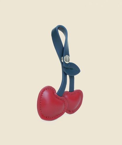 Red cherry heart keychain angled view showing dual heart shape and smooth PU leather finish