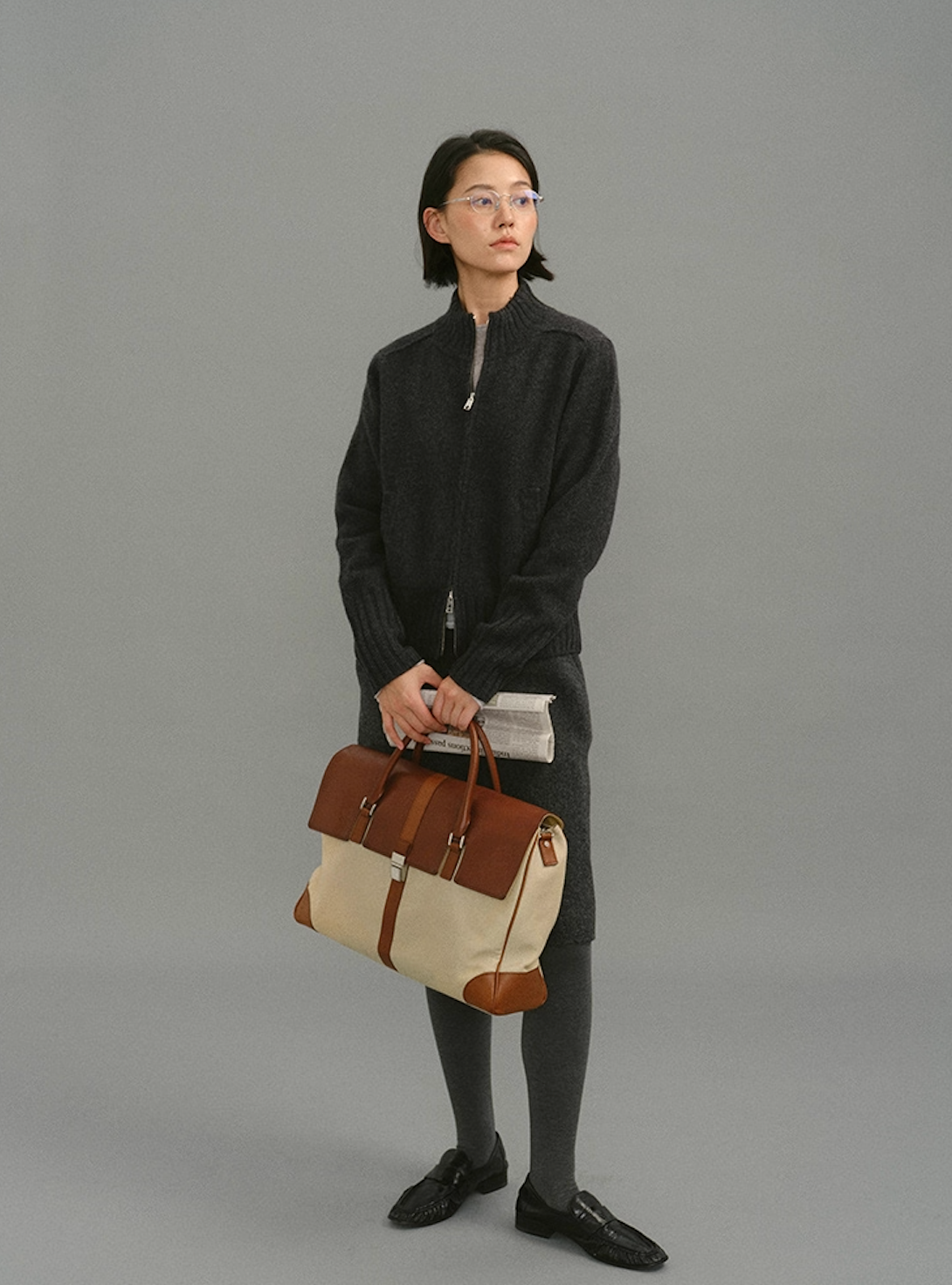 Woman wearing dark charcoal wool zip-up cardigan, full front view against grey background