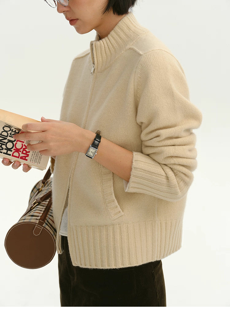 Woman wearing cream wool zip-up cardigan reading a book, side upper-body view
