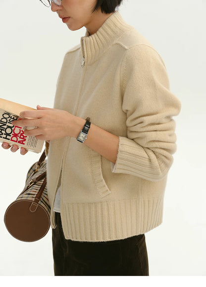 Woman wearing cream wool zip-up cardigan reading a book, side upper-body view