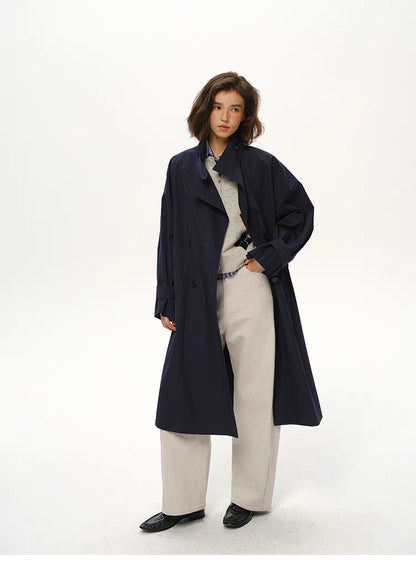 Deep navy trench coat styled with light trousers and soft sweater, front full-body view.