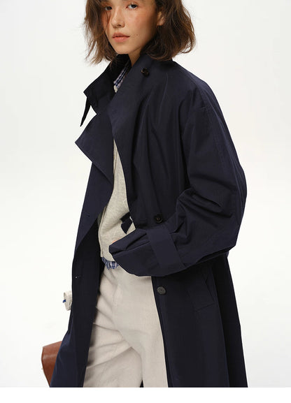 Three-quarter close-up of deep navy trench showing structured lapel and sleeve strap.