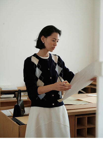 Navy blue Classic Argyle Wool Cardigan styled at desk with white skirt, elegant preppy outfit with argyle knit pattern