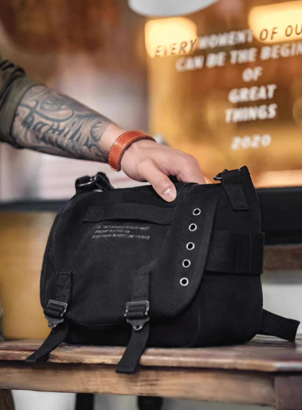 Hand holding black Classic M1961 canvas motorcycle bag highlighting compact structure and rugged design details