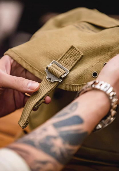 Close-up of khaki Classic M1961 canvas motorcycle bag buckle strap and flap edge showing durable stitching and metal hardware
