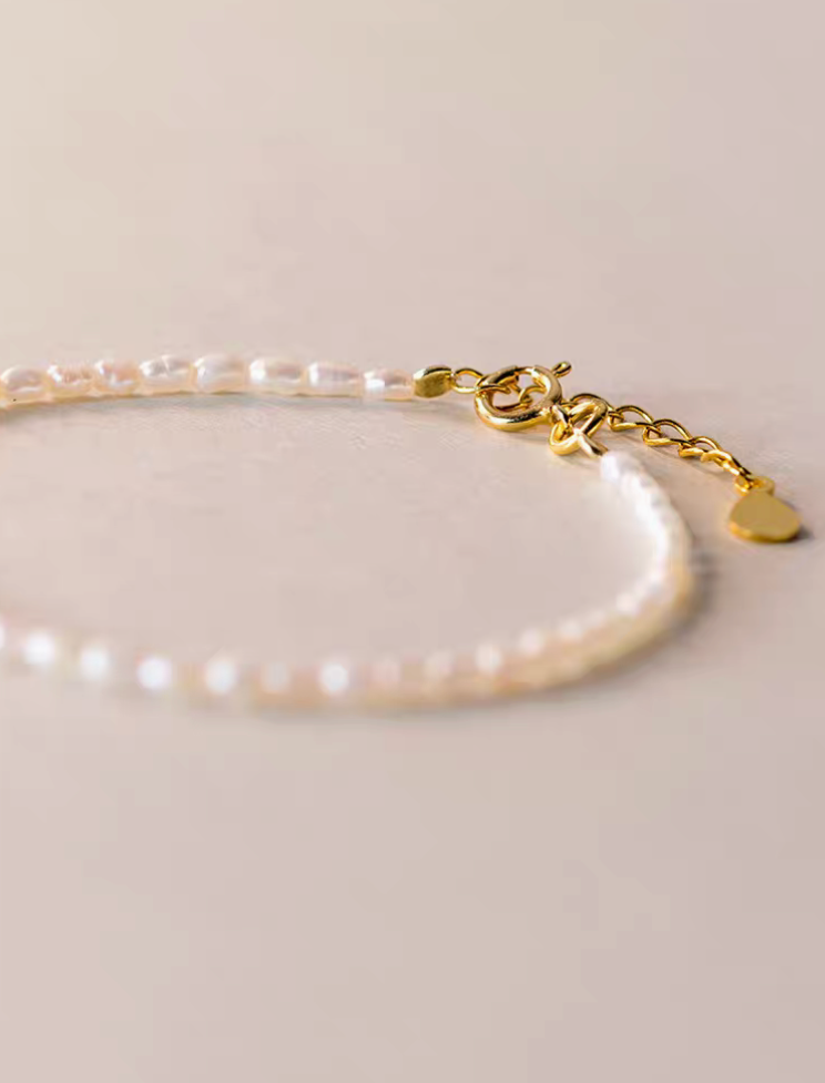 Close-up detail of classic pearl bracelet in natural color showing gold clasp and adjustable extender chain with delicate pearls