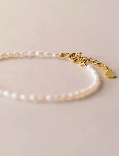 Close-up detail of classic pearl bracelet in natural color showing gold clasp and adjustable extender chain with delicate pearls